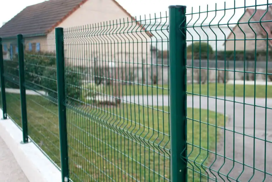 Clôture en panneaux rigides verts le long d'un trottoir