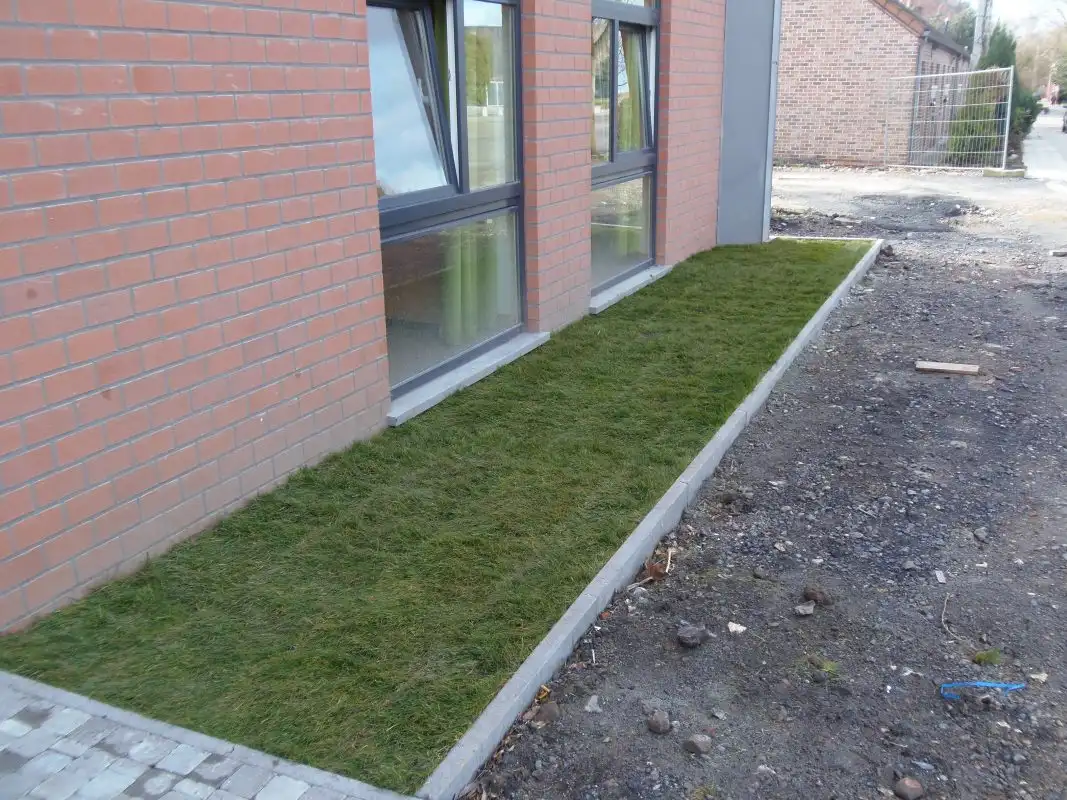 Bande engazonnée et bordure béton le long d’une façade