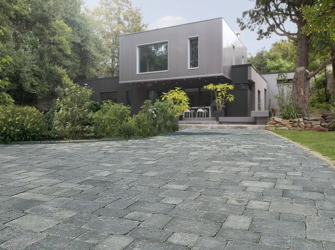 Allée et terrasse en pavés gris vieillis devant une maison moderne